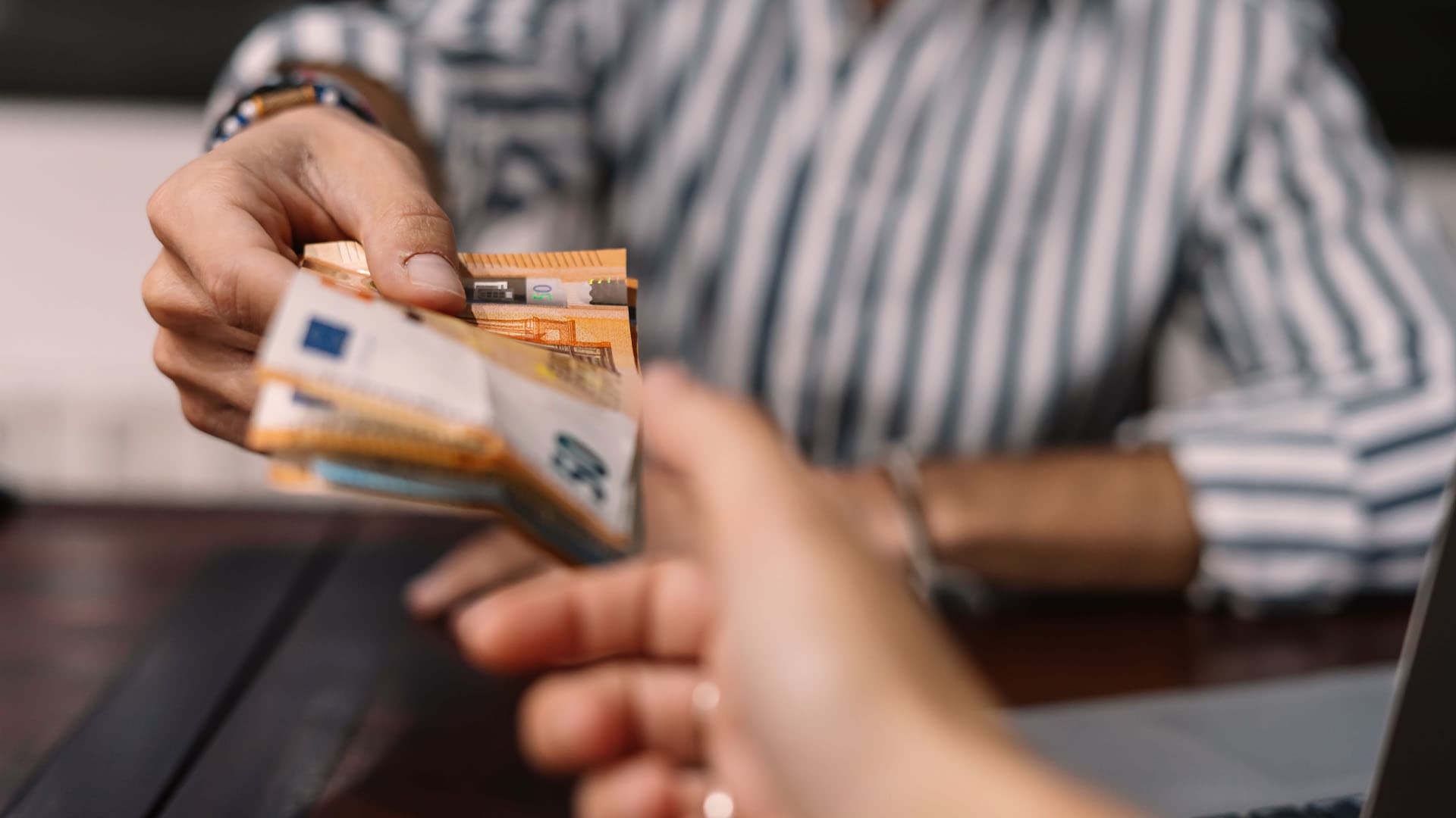 Ein Mann gibt einer Frau mehrere Geldscheine in die Hand.